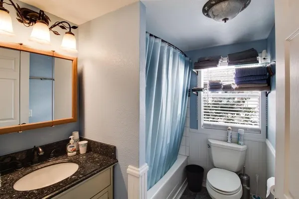 a bathroom with a granite countertop sink toilet and shower