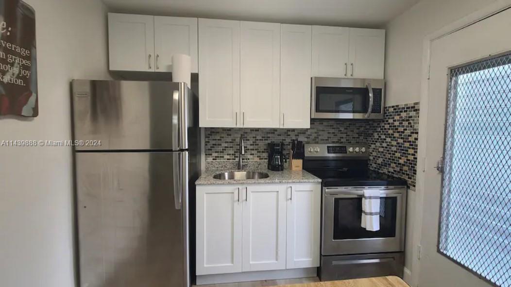649 Southwest 9th Street, Unit 108 Miami, FL 33130 - Photo 5 of 7 a kitchen with a refrigerator sink and cabinets