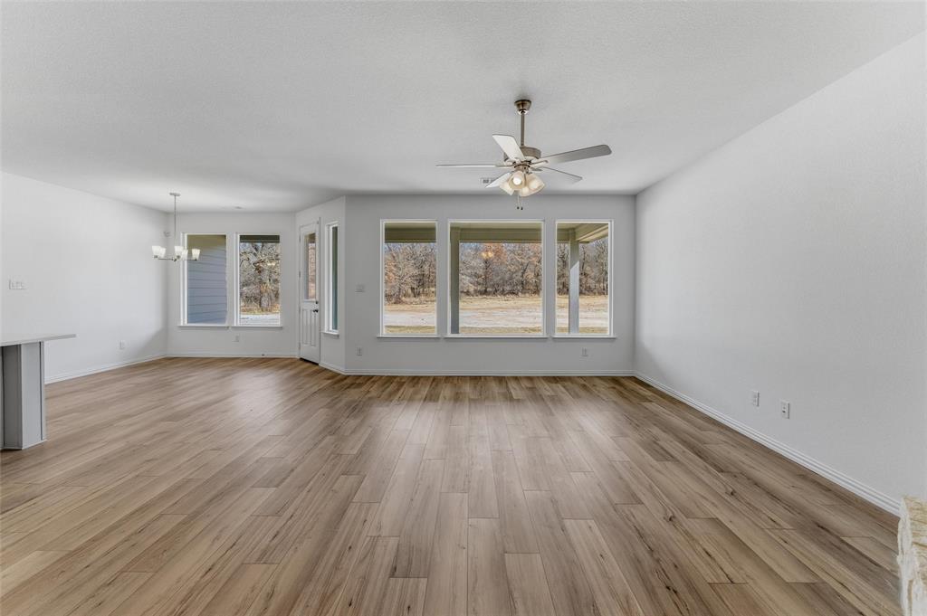 144 Oak Grv Way Springtown, TX 76082 - Photo 12 of 27 an empty room with wooden floor chandelier and windows