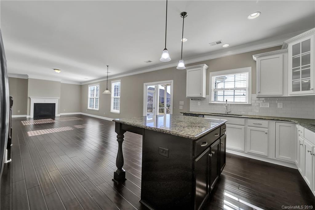 264 Annatto Way Tega Cay, SC 29708 - Photo 11 of 36 a kitchen with granite countertop a stove a sink a dining table and chairs with wooden floor