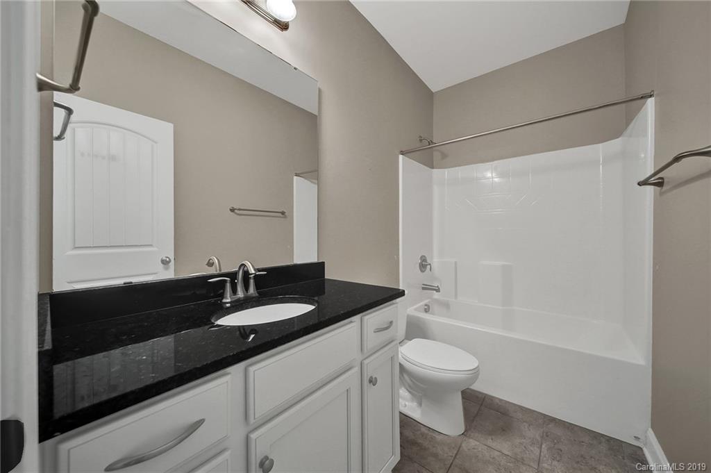 264 Annatto Way Tega Cay, SC 29708 - Photo 19 of 36 a bathroom with a granite countertop sink a toilet a mirror and shower
