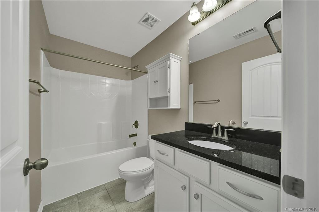 264 Annatto Way Tega Cay, SC 29708 - Photo 29 of 36 a bathroom with a granite countertop sink a toilet a mirror and shower