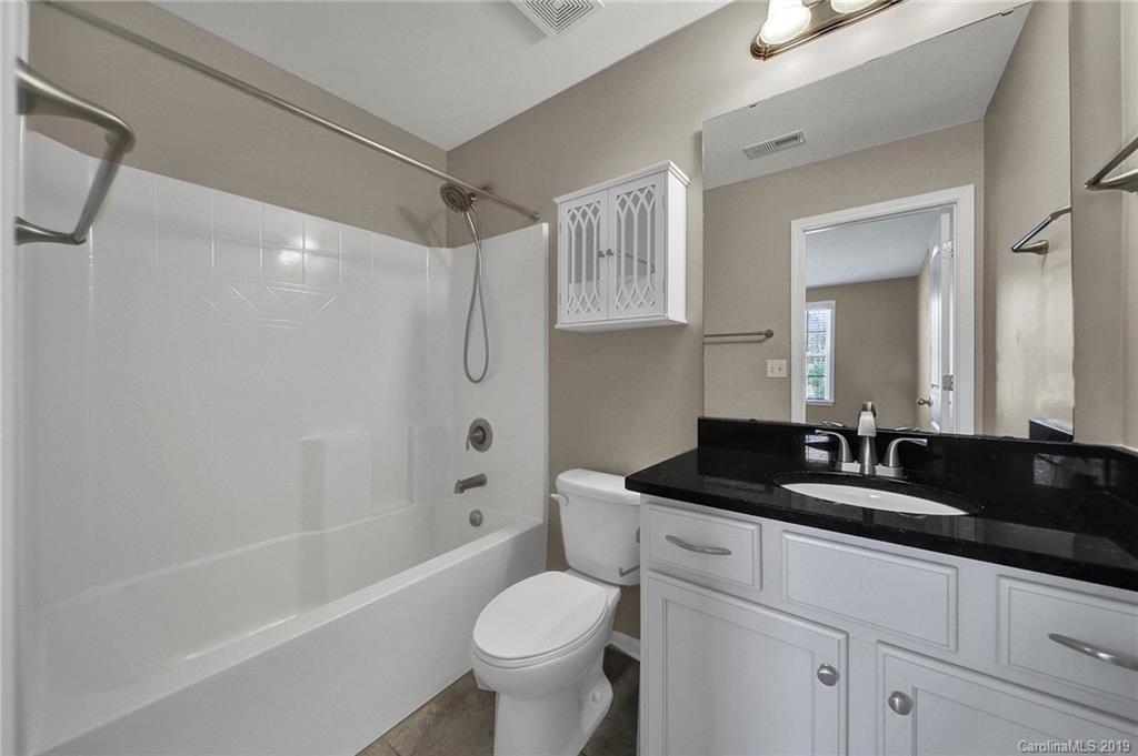 264 Annatto Way Tega Cay, SC 29708 - Photo 32 of 36 a bathroom with a granite countertop sink a toilet a mirror a bathtub and shower