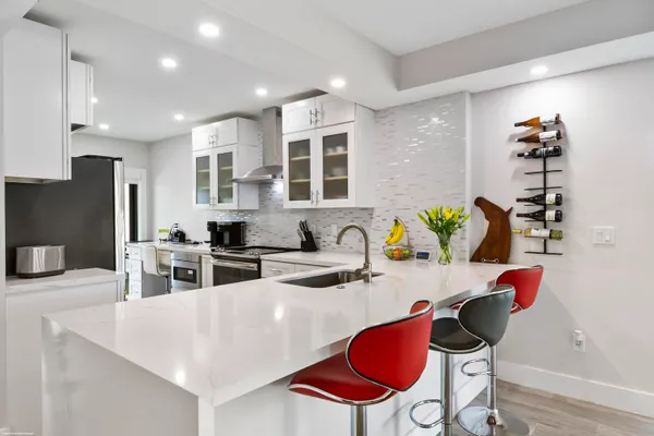a kitchen with stainless steel appliances kitchen island granite countertop a dining table chairs and a refrigerator