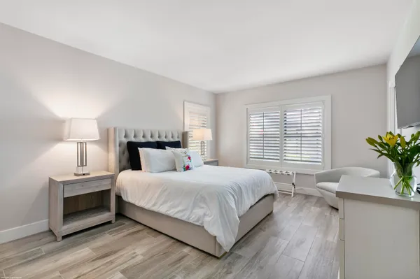 a bedroom with a bed a potted plant on table and a window