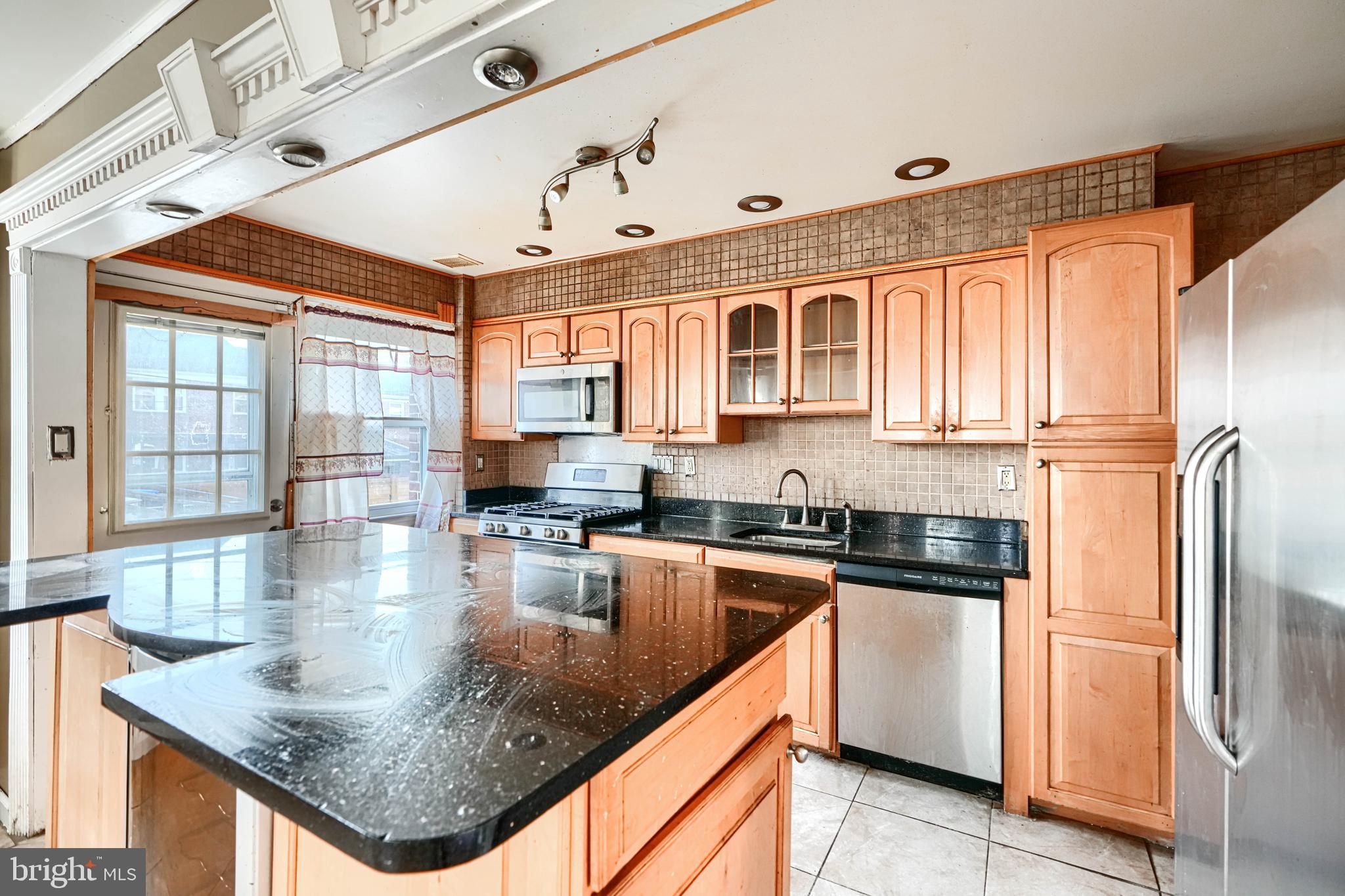 1517 Medford Road Baltimore, MD 21218 - Photo 13 of 27 a kitchen with stainless steel appliances granite countertop a refrigerator a sink dishwasher a stove and a dining table with wooden cabinet