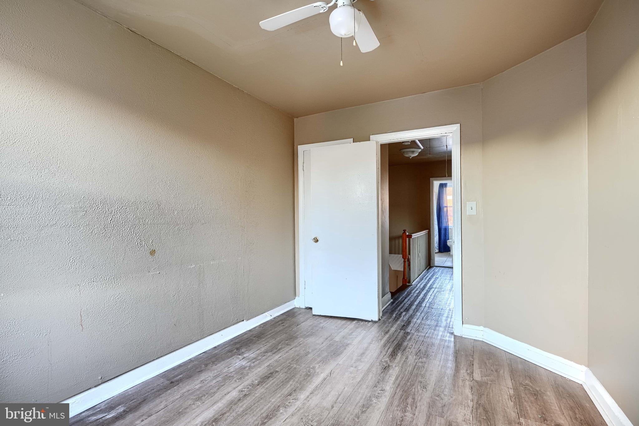 1517 Medford Road Baltimore, MD 21218 - Photo 16 of 27 an empty room with wooden floor and chandelier