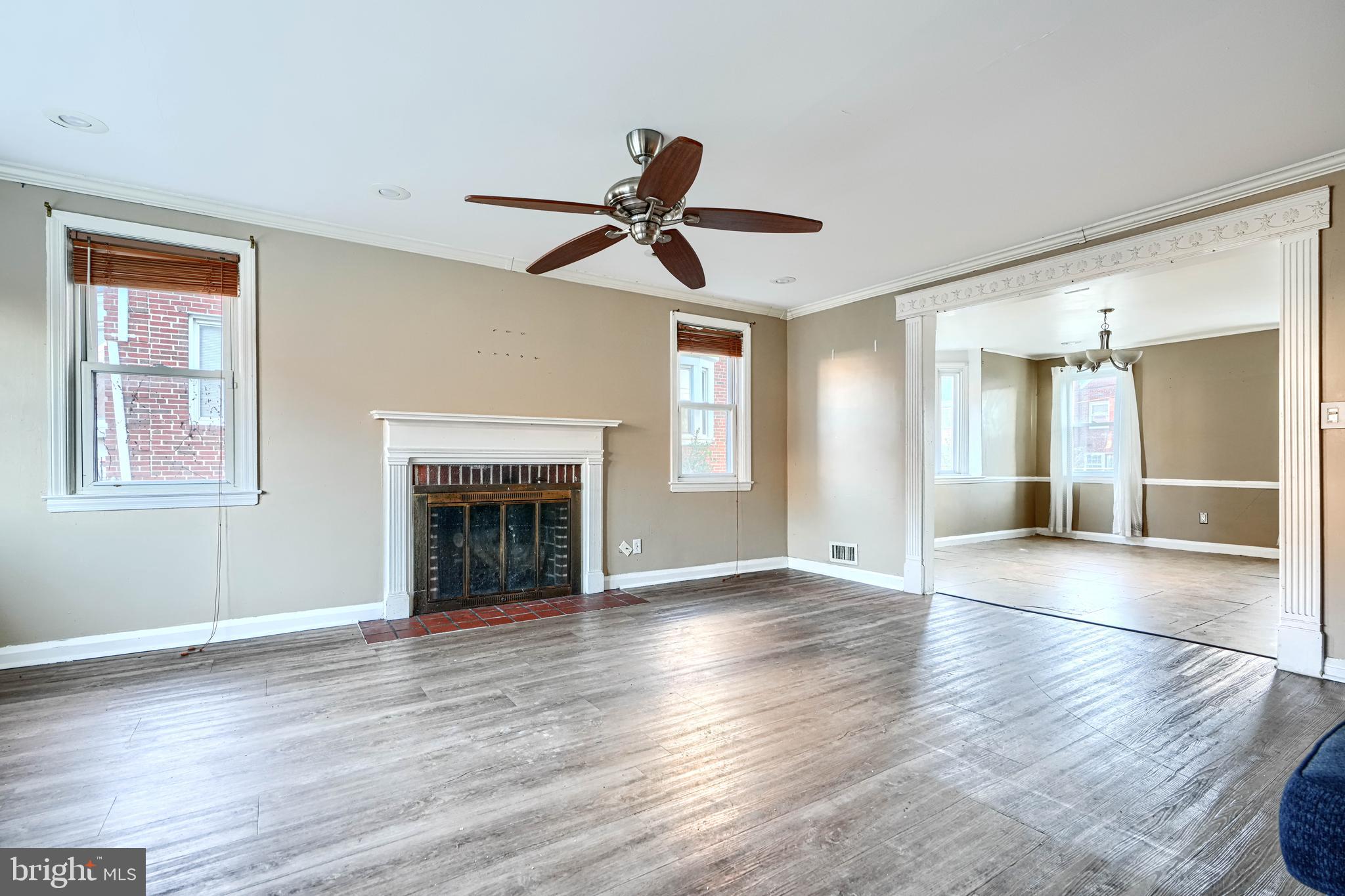 1517 Medford Road Baltimore, MD 21218 - Photo 5 of 27 a view of an empty room with wooden floor fireplace and a window