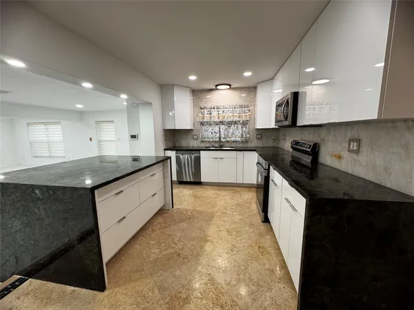 a large kitchen with stainless steel appliances granite countertop a sink a stove and a refrigerator