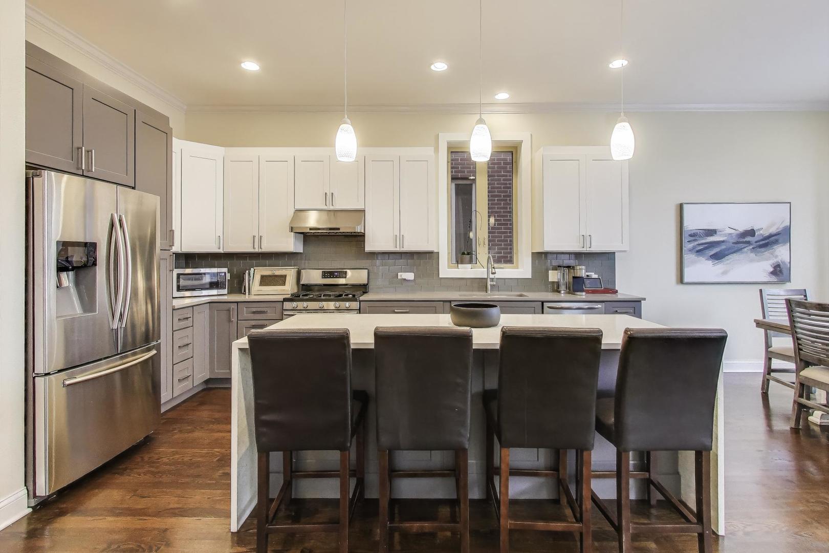 1045 West 34th Place Chicago, IL 60608 - Photo 9 of 35 a kitchen with stainless steel appliances granite countertop a dining table chairs refrigerator and sink