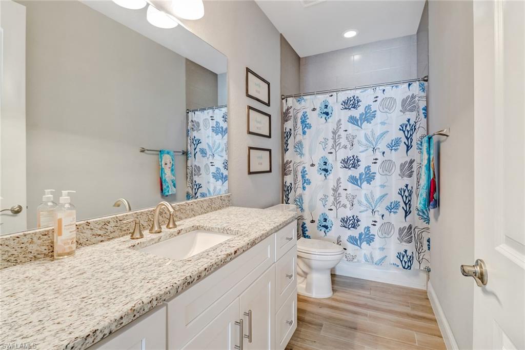 8476 Grove Road Fort Myers, FL 33967 - Photo 21 of 25 a bathroom with a granite countertop sink a toilet and shower curtain