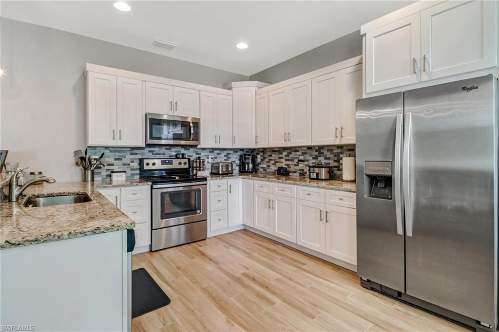 8476 Grove Road Fort Myers, FL 33967 - Photo 6 of 25 a kitchen with granite countertop a refrigerator stove and microwave