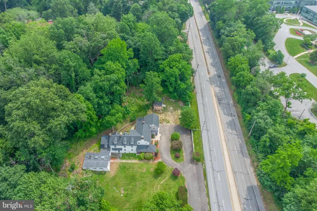 an aerial view of residential house with outdoor space and trees all around
