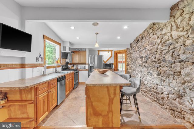 a kitchen with stainless steel appliances kitchen island granite countertop a sink and a black cabinets