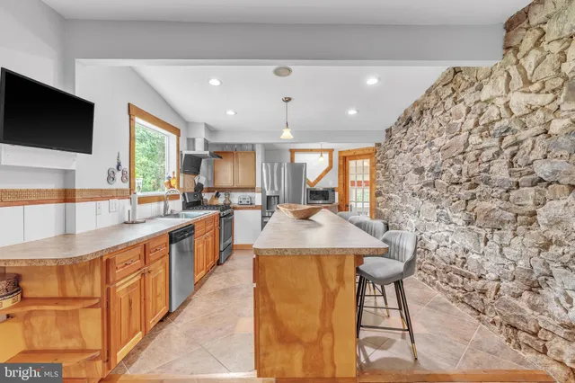 a kitchen with stainless steel appliances kitchen island granite countertop a sink and a black cabinets