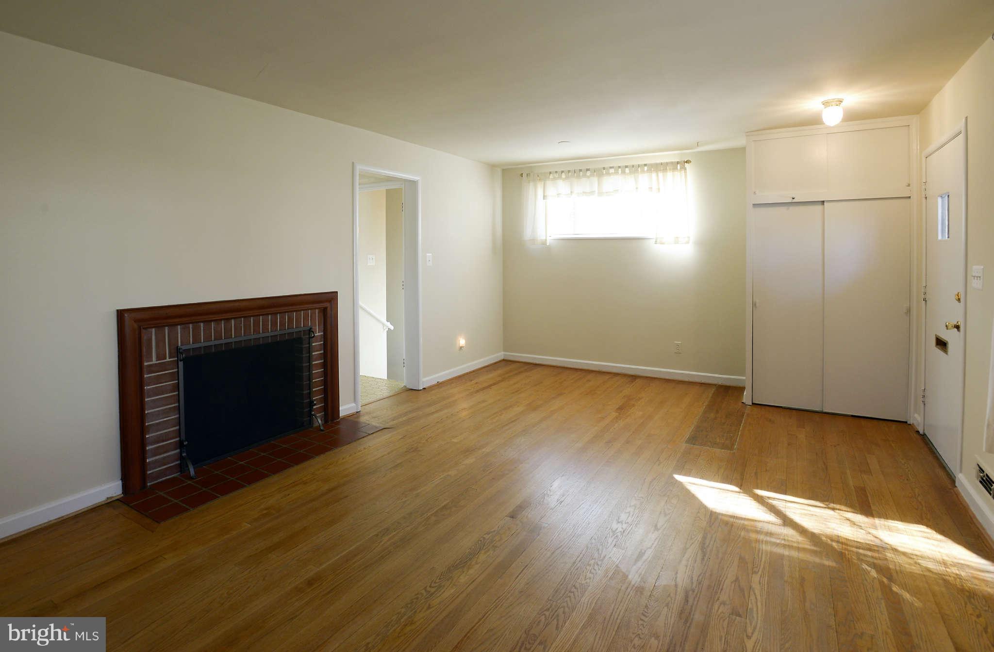 3913 Isbell Street Silver Spring, MD 20906 - Photo 4 of 23 an empty room with wooden floor a fireplace and windows