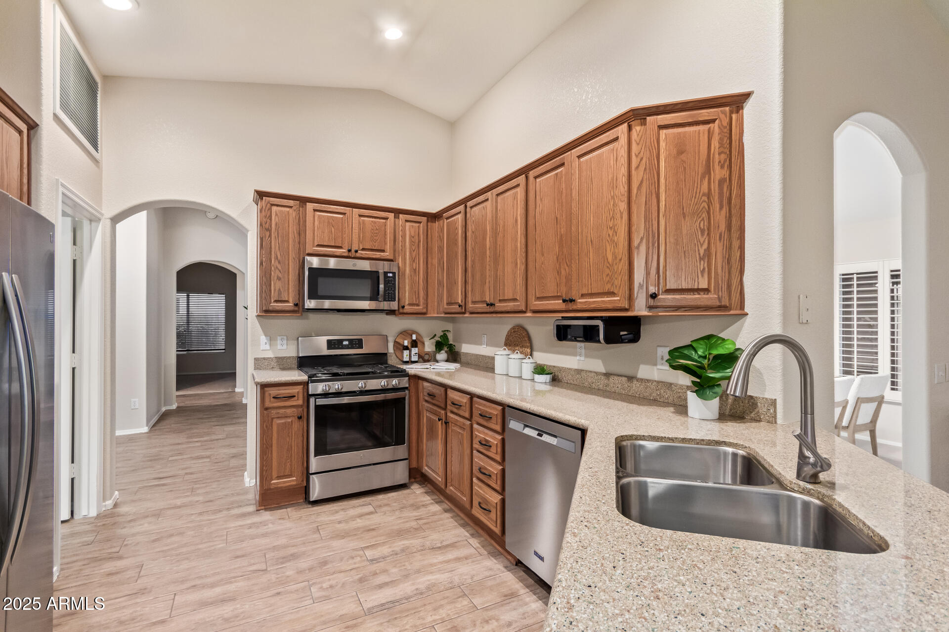 15596 West Flower Court Goodyear, AZ 85395 - Photo 18 of 35 a kitchen with stainless steel appliances granite countertop a sink a stove a refrigerator cabinets and a microwave oven