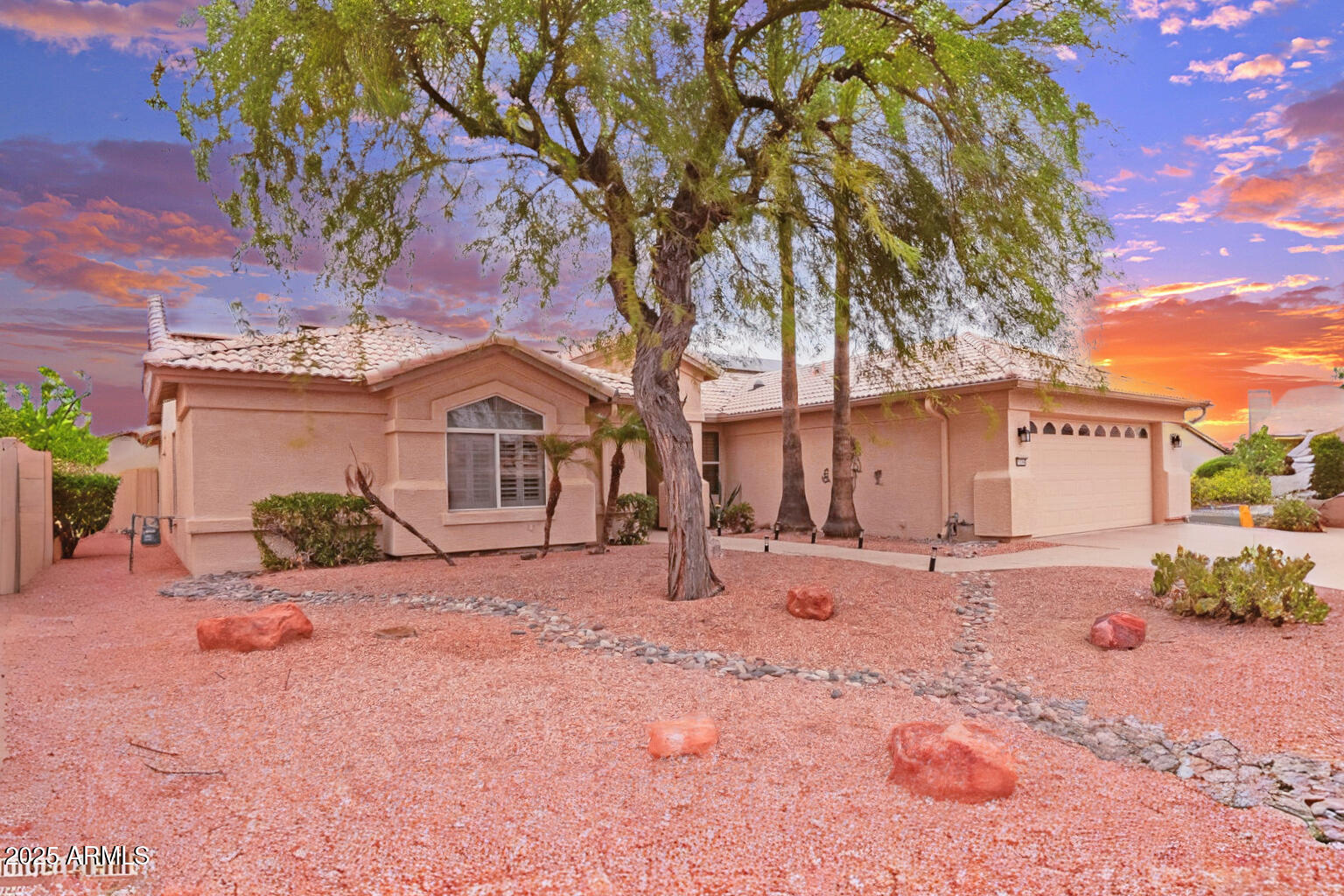 15596 West Flower Court Goodyear, AZ 85395 - Photo 2 of 35 a front view of a house with a dirt yard and a large tree