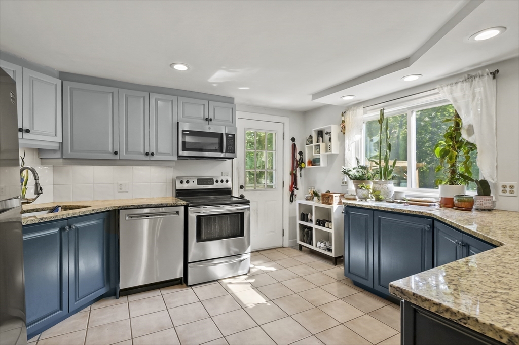 9 Oregon Road Southborough, MA 01772 - Photo 8 of 27 a kitchen with stainless steel appliances granite countertop a stove top oven a sink dishwasher a dining table and chairs with wooden floor