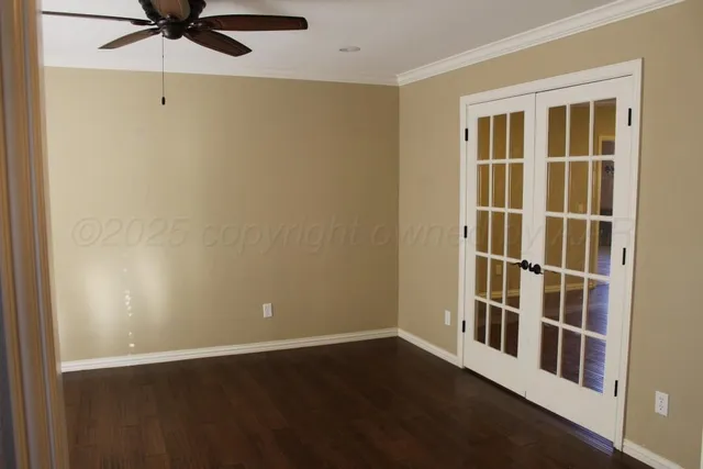 an empty room with wooden floor and a ceiling fan