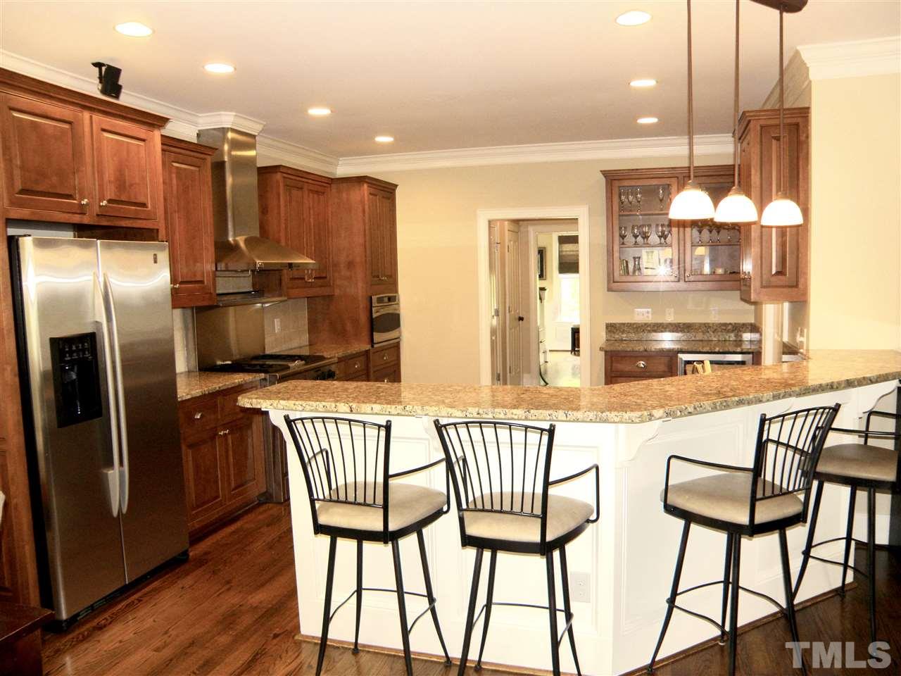 2702 Bedford Avenue Raleigh, NC 27607 - Photo 9 of 25 a kitchen with stainless steel appliances kitchen island granite countertop a table chairs and a refrigerator