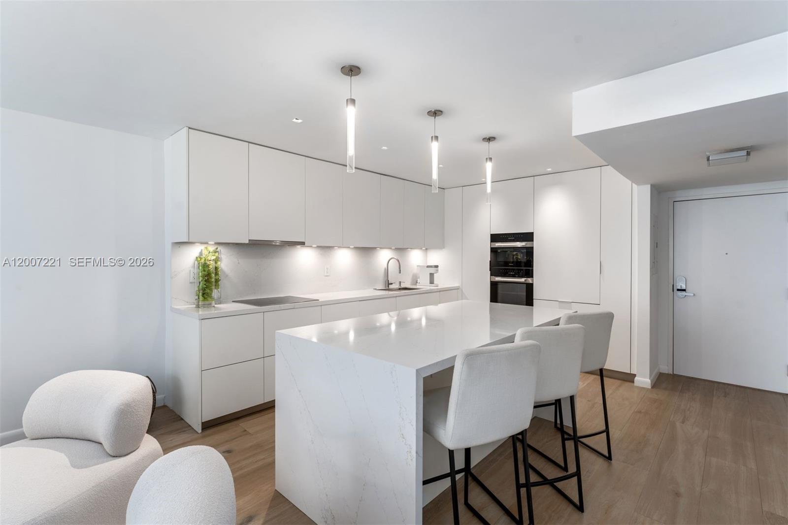 2301 Collins Avenue, Unit 902 Miami Beach, FL 33139 - Photo 8 of 22 a kitchen with stainless steel appliances granite countertop a sink a stove a refrigerator a microwave oven with white cabinets and wooden floor