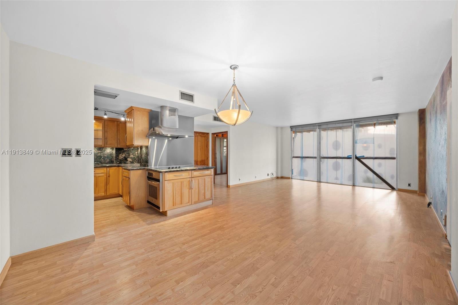 a view of an empty room with window and wooden floor