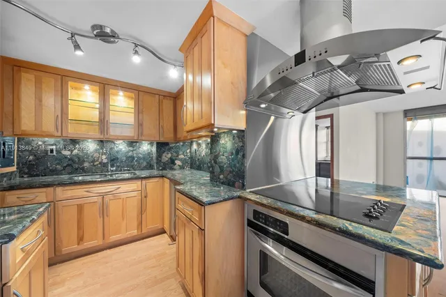 a kitchen with stainless steel appliances granite countertop a sink a stove and cabinets