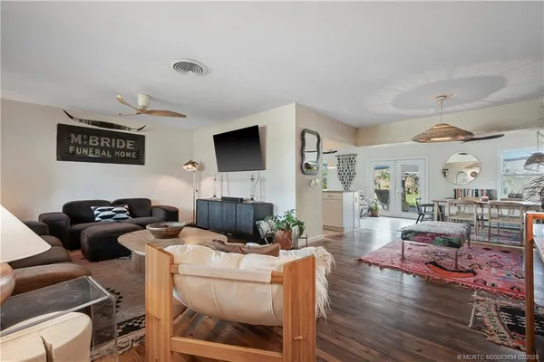 a view of a dining room and livingroom with furniture wooden floor a rug a painting and a chandelier