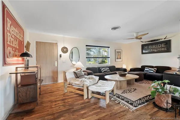 a living room with stainless steel appliances furniture a rug and a large window