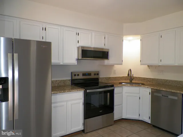 a kitchen with granite countertop white cabinets sink and stainless steel appliances