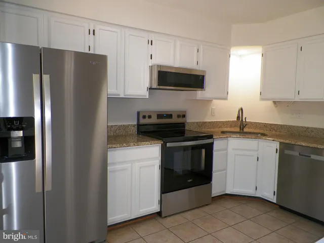 a kitchen with cabinets stainless steel appliances and a counter space