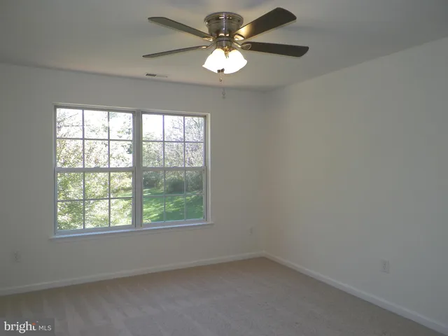 an empty room with a window and a fan