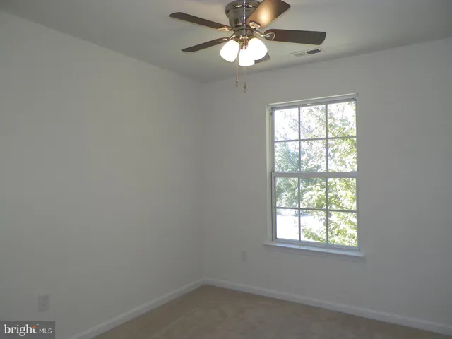 an empty room with a window and a fan