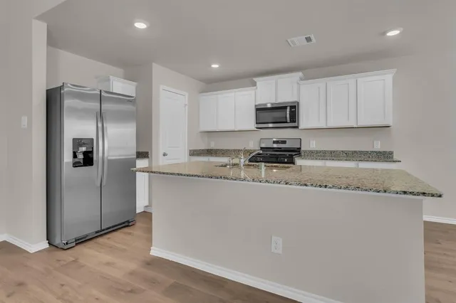 a kitchen with stainless steel appliances granite countertop a refrigerator a stove a sink and a granite counter tops