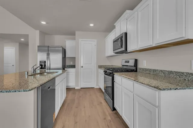 a kitchen with stainless steel appliances granite countertop a sink stove and cabinets