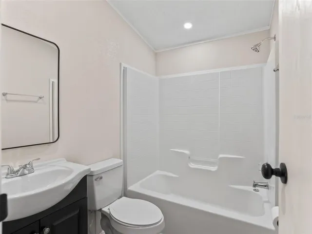 a bathroom with a bathtub shower sink vanity mirror and toilet