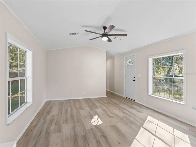 a view of empty room with wooden floor and fan