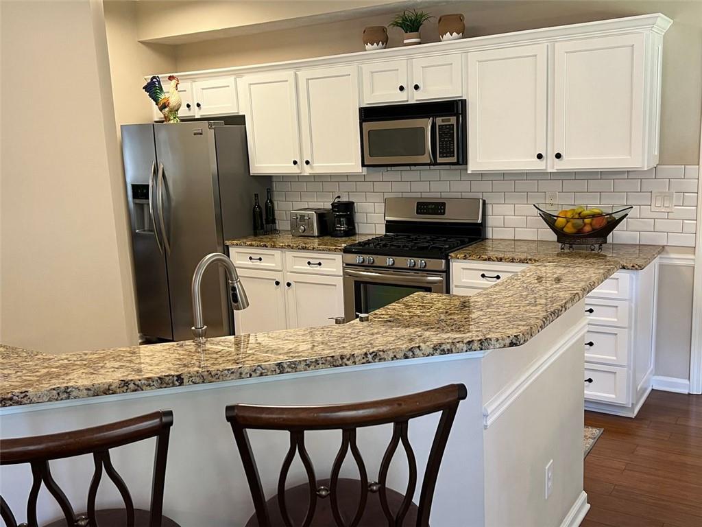 2430 Jakin Way Suwanee, GA 30024 - Photo 15 of 55 a kitchen with stainless steel appliances granite countertop a stove a sink a microwave a refrigerator and white cabinets