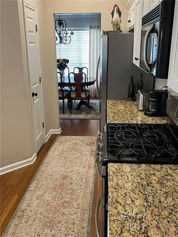 a kitchen with granite countertop a sink cabinets and wooden floor