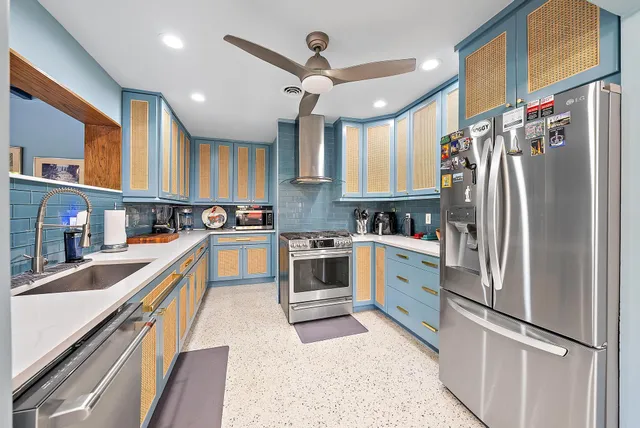 a kitchen with stainless steel appliances granite countertop a refrigerator a sink dishwasher a stove and a dining table with wooden floor