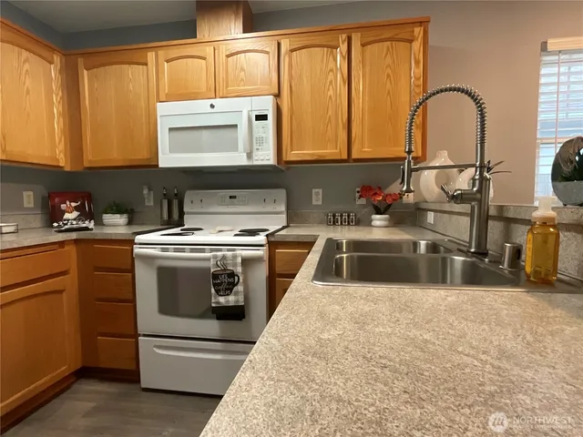a kitchen with stainless steel appliances granite countertop a stove a sink and a microwave