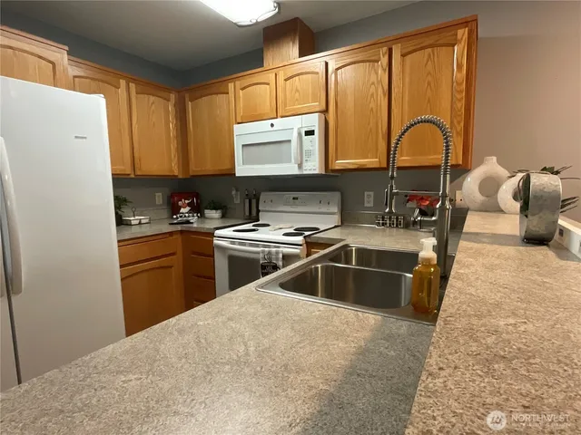 a kitchen with a sink a counter top space cabinets a stove a chimney and a refrigerator