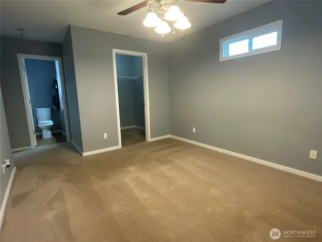 an empty room with a chandelier fan and windows