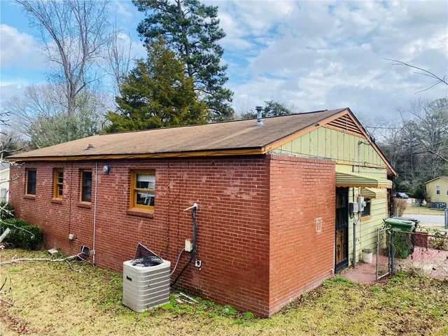 a view of a house that has a small yard and large trees