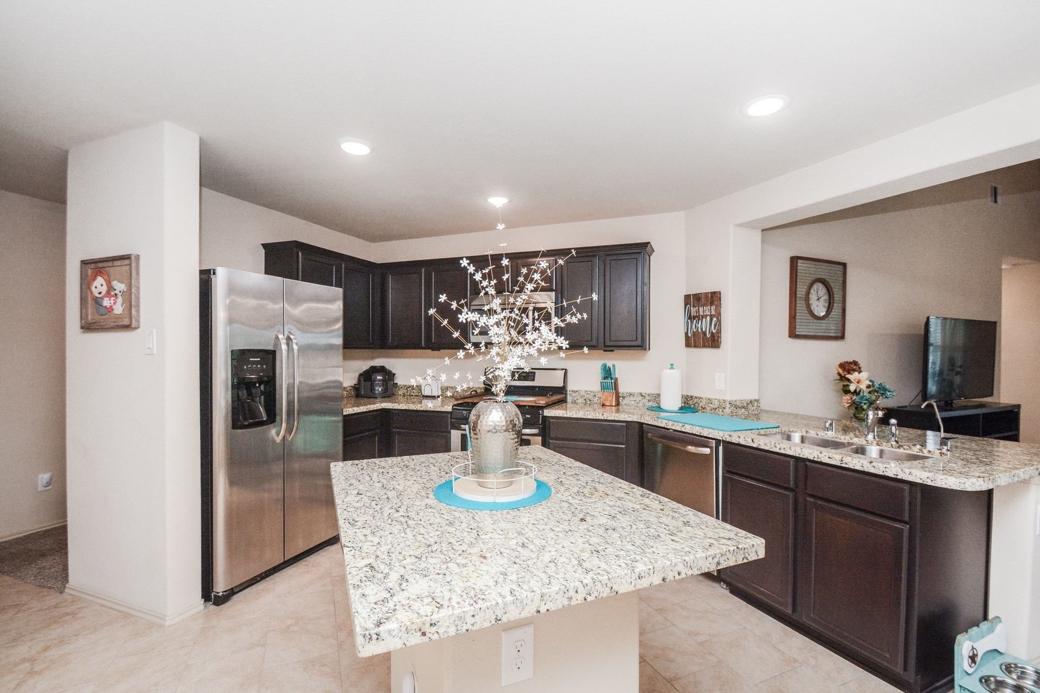 23318 Dukes Run Drive Spring, TX 77373 - Photo 6 of 41 This kitchen features modern stainless steel appliances, dark wood cabinetry, and granite countertops. It has a spacious island with decorative elements, recessed lighting, and an open layout connecting to the living area.