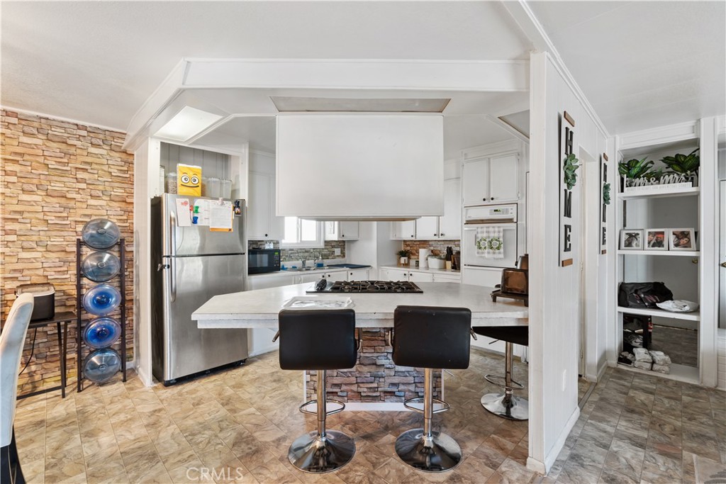 1000 Windy Pass, Unit 146 Barstow, CA 92311 - Photo 7 of 29 a living room with furniture a rug and kitchen view