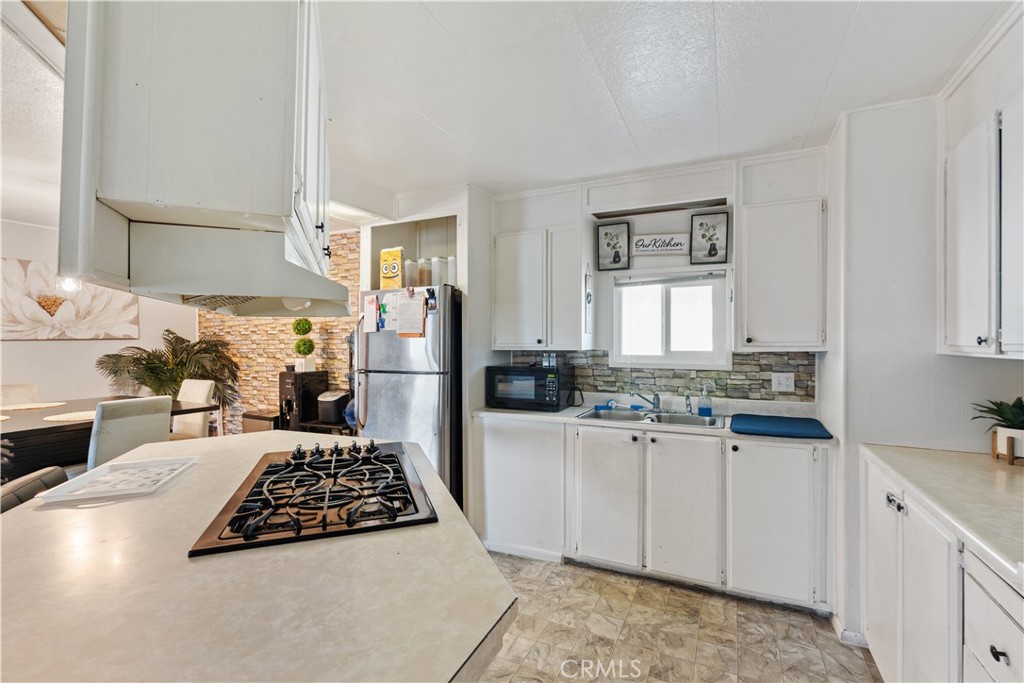 1000 Windy Pass, Unit 146 Barstow, CA 92311 - Photo 10 of 29 a kitchen with a stove a sink cabinets and a window