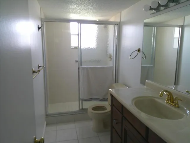 a bathroom with a granite countertop sink a toilet a mirror and shower