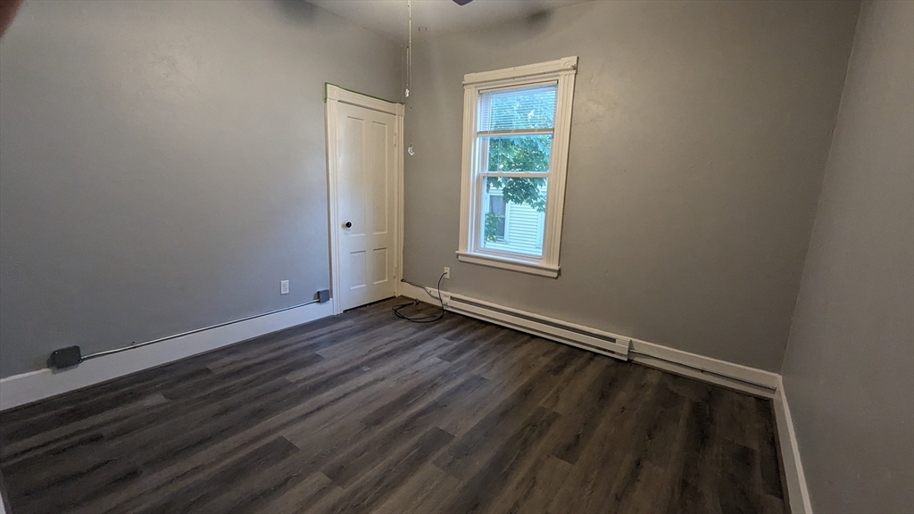 104 Rodney Street, Unit 2 Worcester, MA 01605 - Photo 4 of 7 an empty room with wooden floor and windows